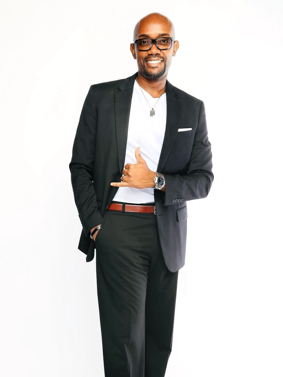 Jeffrey full length in a dark suit, one hand at his jacket, smiling